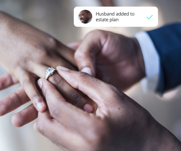 Closeup of a groom's hand putting a wedding ring on the bride's finger