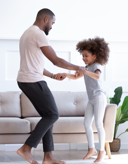 A dad teaches his young daughter to dance.