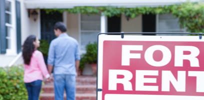 Couple viewing home with 'for rent' sign in front